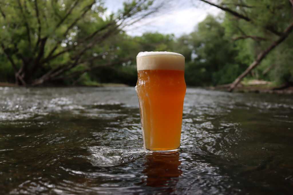 A pint of our Straight River IPA sitting in the stream of the Straight River